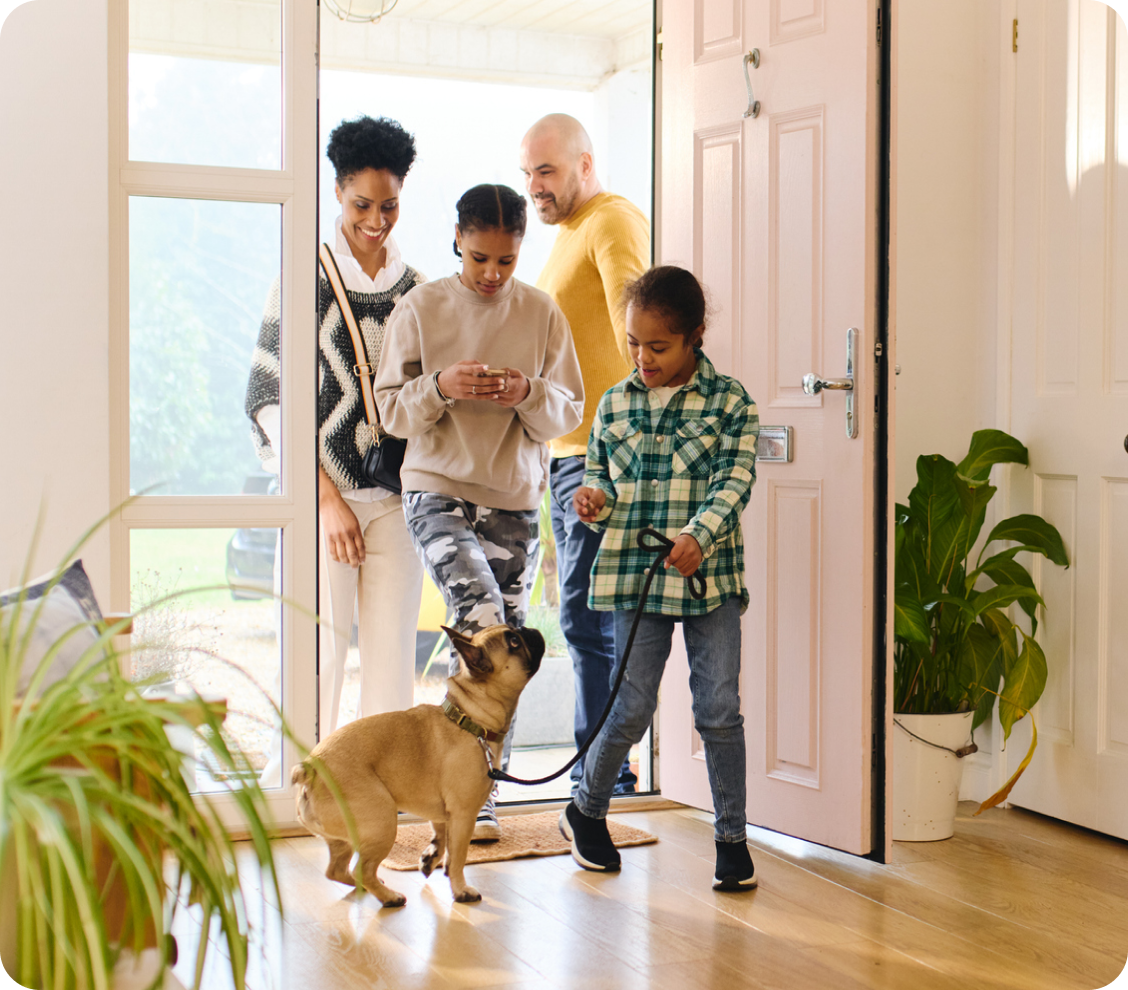 A family with their dog returning home from a walk.