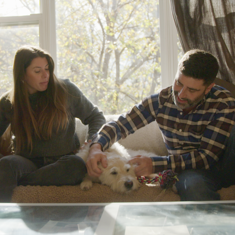 A couple with their two dogs on the couch.