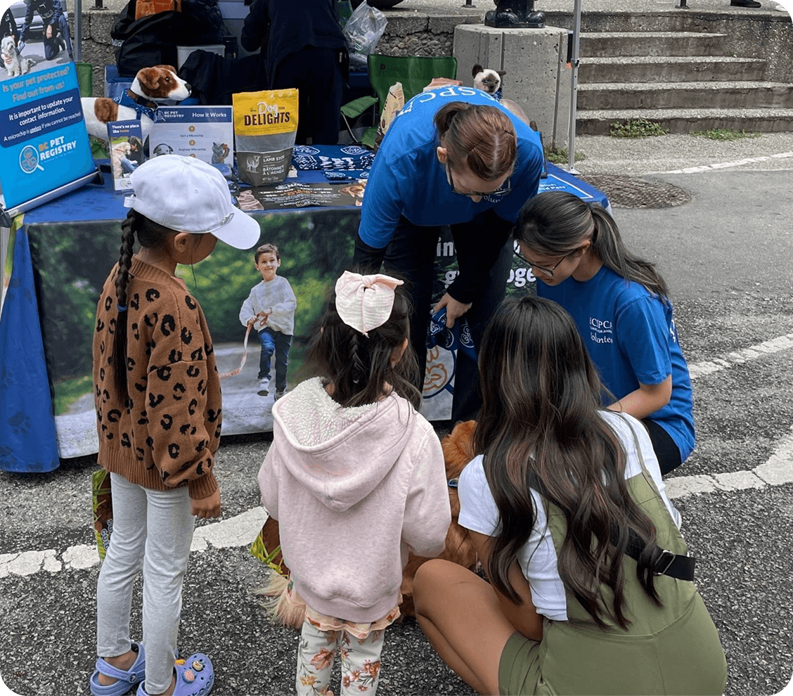 Volunteers from a pet shelter with a rescue dog surrounded by children.